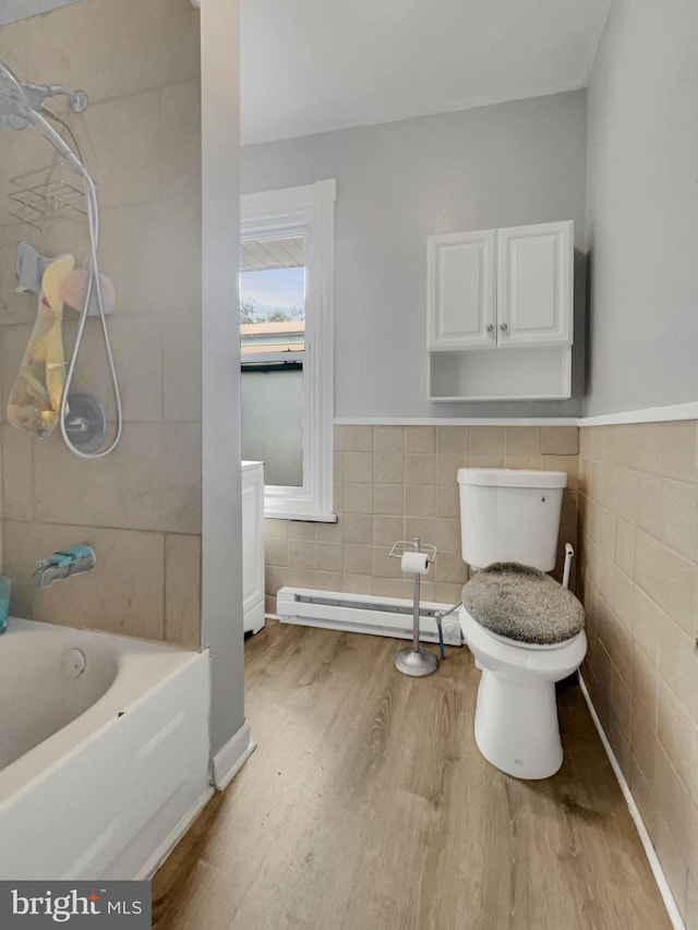 bathroom featuring tile walls, hardwood / wood-style floors, tiled shower / bath combo, and toilet