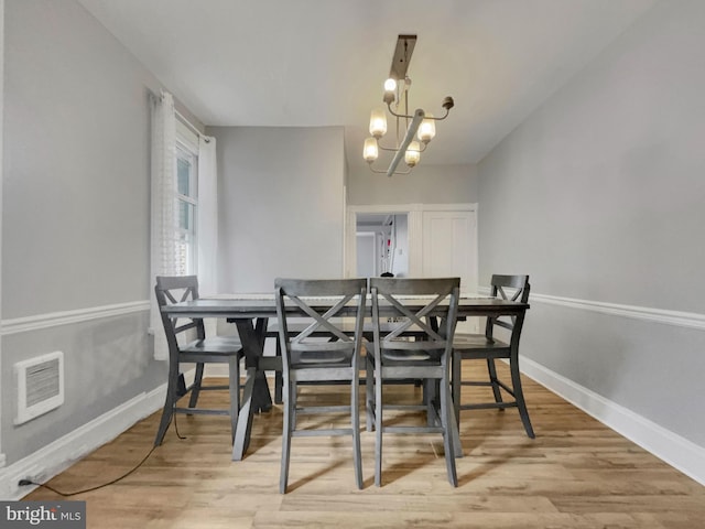 dining area featuring wood-type flooring and a chandelier