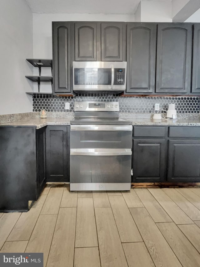 kitchen with backsplash, stainless steel appliances, and light hardwood / wood-style flooring