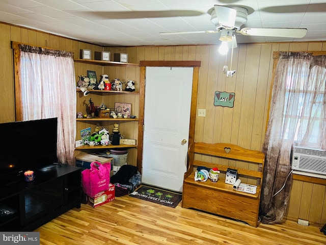 interior space featuring light hardwood / wood-style floors, wood walls, and ceiling fan