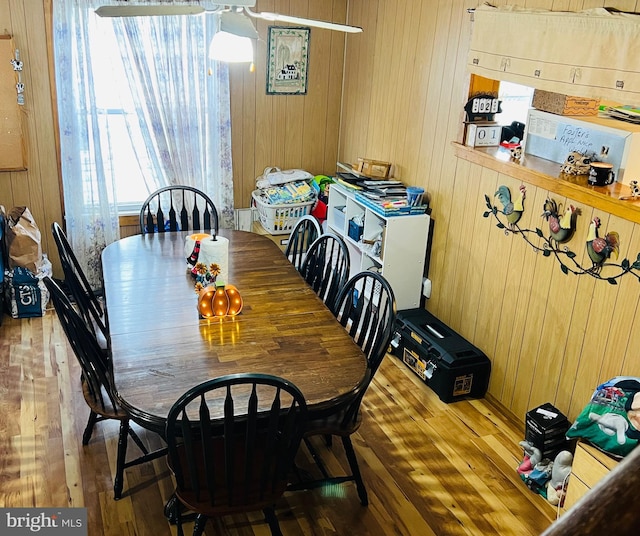 dining space with hardwood / wood-style floors and wooden walls