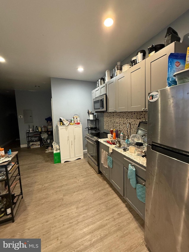 kitchen featuring gray cabinets, stainless steel appliances, tasteful backsplash, and light hardwood / wood-style flooring