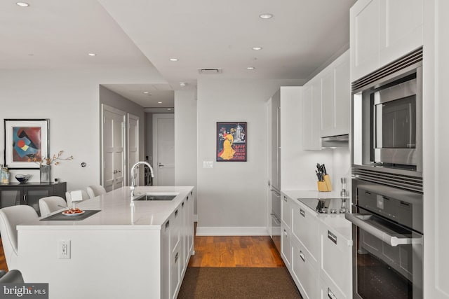 kitchen featuring white cabinets, black appliances, a kitchen island with sink, and sink