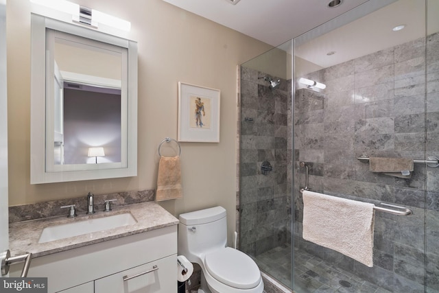 bathroom with a shower with shower door, vanity, and toilet