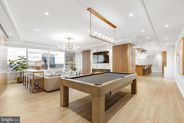 recreation room with billiards, a fireplace, light hardwood / wood-style floors, and indoor bar