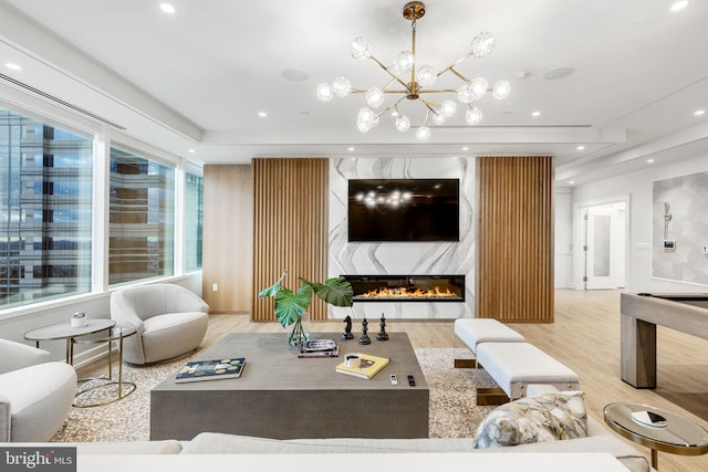 living room with an inviting chandelier, light hardwood / wood-style floors, and a high end fireplace