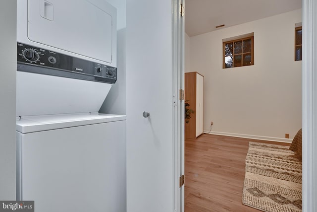 washroom with light wood-type flooring and stacked washer and dryer