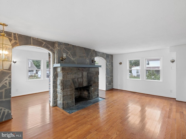 unfurnished living room with wood-type flooring and a stone fireplace