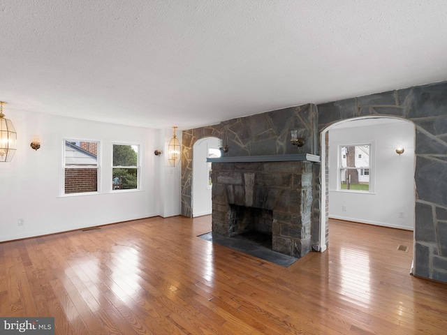 unfurnished living room with a textured ceiling, a fireplace, and hardwood / wood-style floors