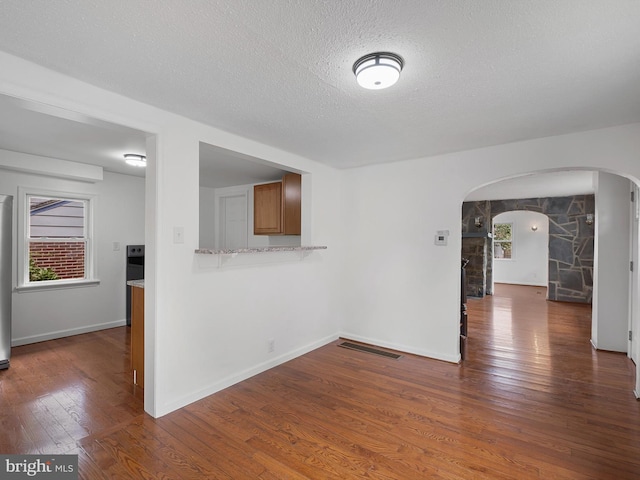 unfurnished room with a textured ceiling and dark wood-type flooring