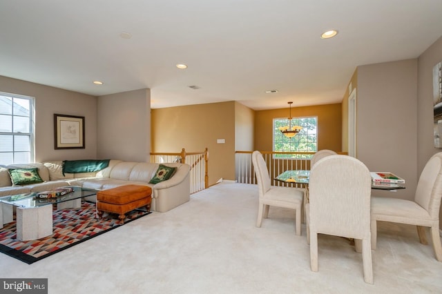 carpeted dining area with a notable chandelier and a healthy amount of sunlight