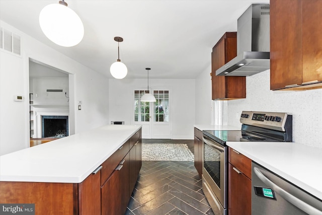 kitchen with hanging light fixtures, tasteful backsplash, wall chimney exhaust hood, a kitchen island, and stainless steel appliances