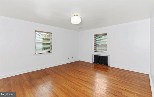 unfurnished living room with wood-type flooring and radiator heating unit