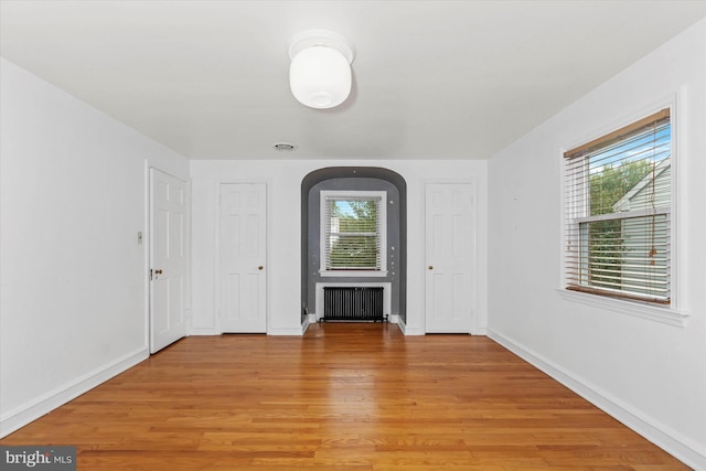 unfurnished room featuring radiator and light hardwood / wood-style floors