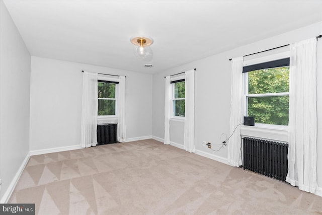 empty room with radiator, a wealth of natural light, and light colored carpet