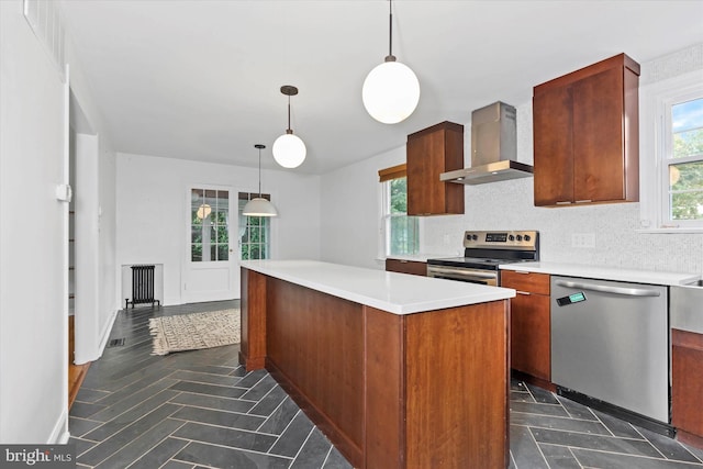 kitchen with hanging light fixtures, decorative backsplash, a kitchen island, stainless steel appliances, and wall chimney range hood