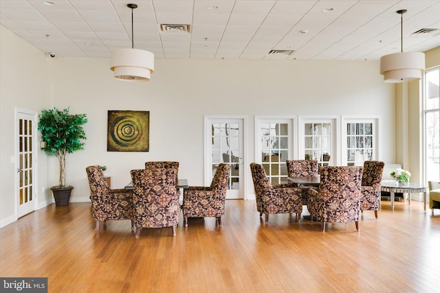 dining room featuring a drop ceiling, a towering ceiling, and light hardwood / wood-style flooring