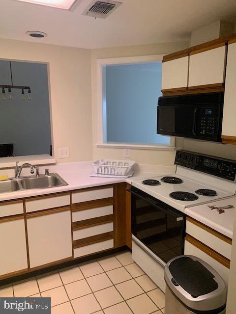 kitchen with light tile patterned flooring, sink, white electric stove, and white cabinetry