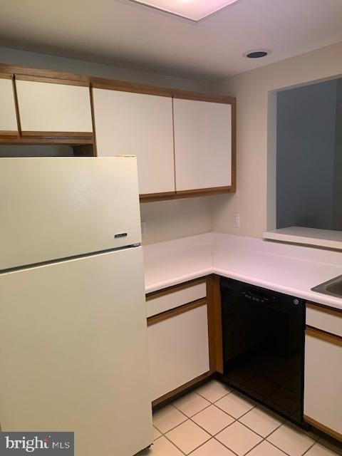 kitchen featuring light tile patterned floors, white cabinets, dishwasher, and white fridge