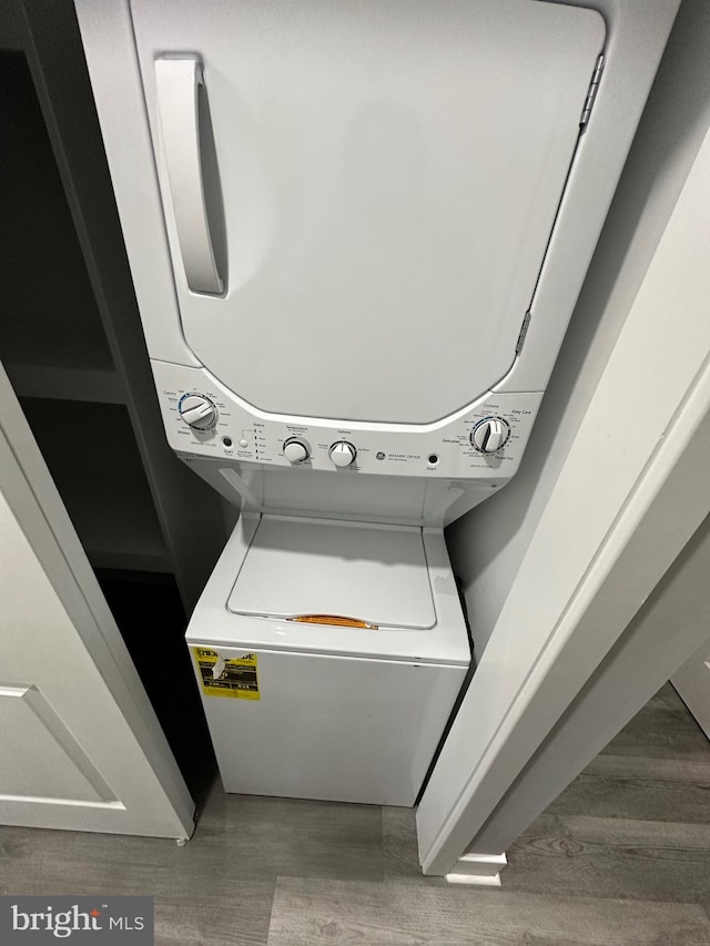 washroom with wood-type flooring and stacked washer / drying machine