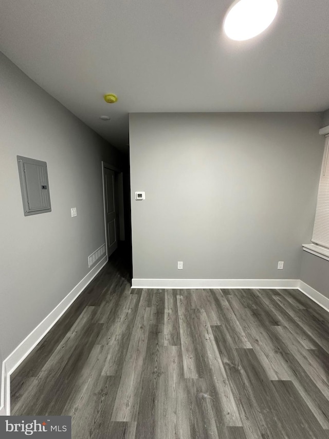 unfurnished room with electric panel and dark wood-type flooring