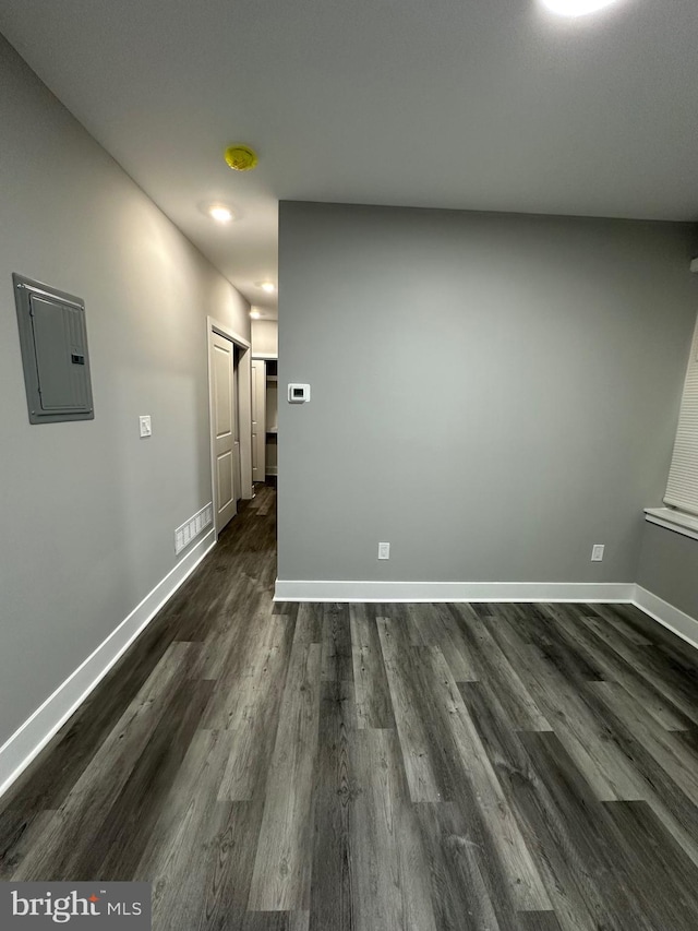 unfurnished room with electric panel and dark wood-type flooring