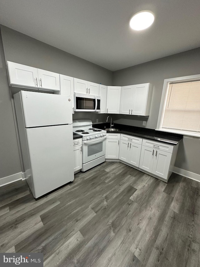 kitchen featuring white appliances, white cabinetry, and dark wood-type flooring