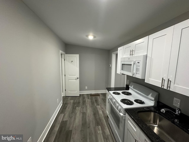 kitchen with sink, white appliances, white cabinetry, dark hardwood / wood-style floors, and dark stone counters