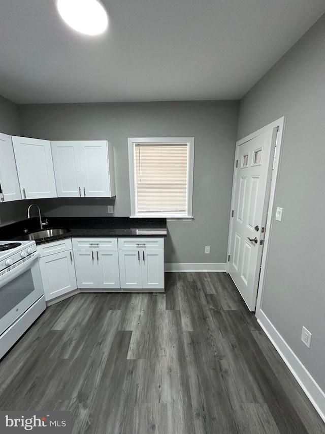 kitchen with white stove, white cabinetry, sink, and dark hardwood / wood-style floors