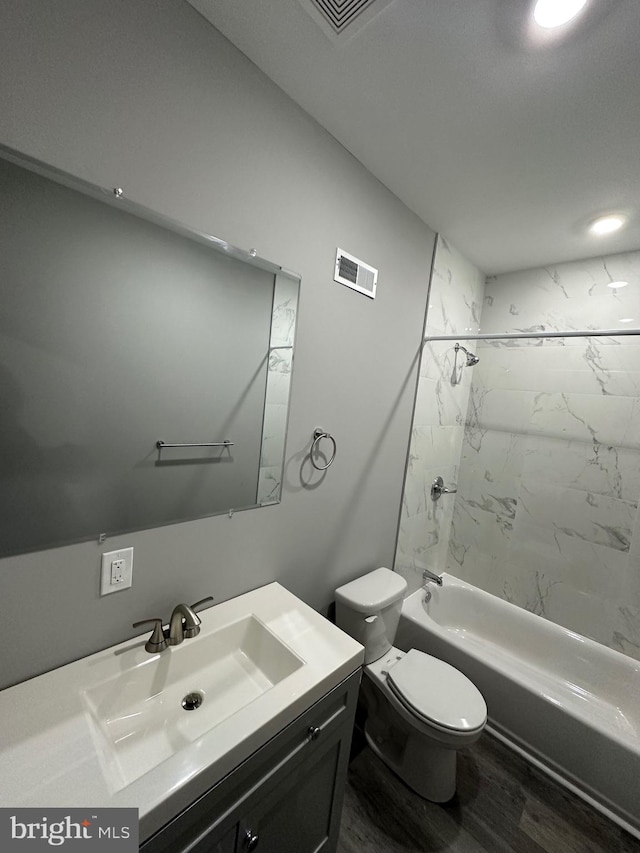 full bathroom featuring tiled shower / bath combo, hardwood / wood-style flooring, vanity, and toilet