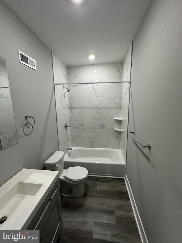 full bathroom with hardwood / wood-style floors, tiled shower / bath, vanity, and toilet