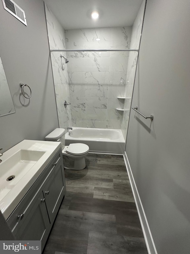 full bathroom with hardwood / wood-style floors, vanity, tiled shower / bath combo, and toilet