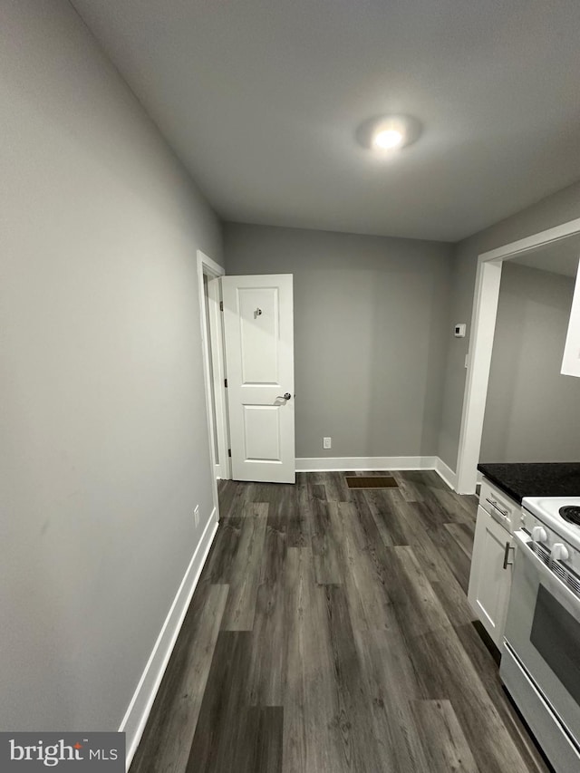 interior space featuring white cabinets, white electric range oven, and dark wood-type flooring