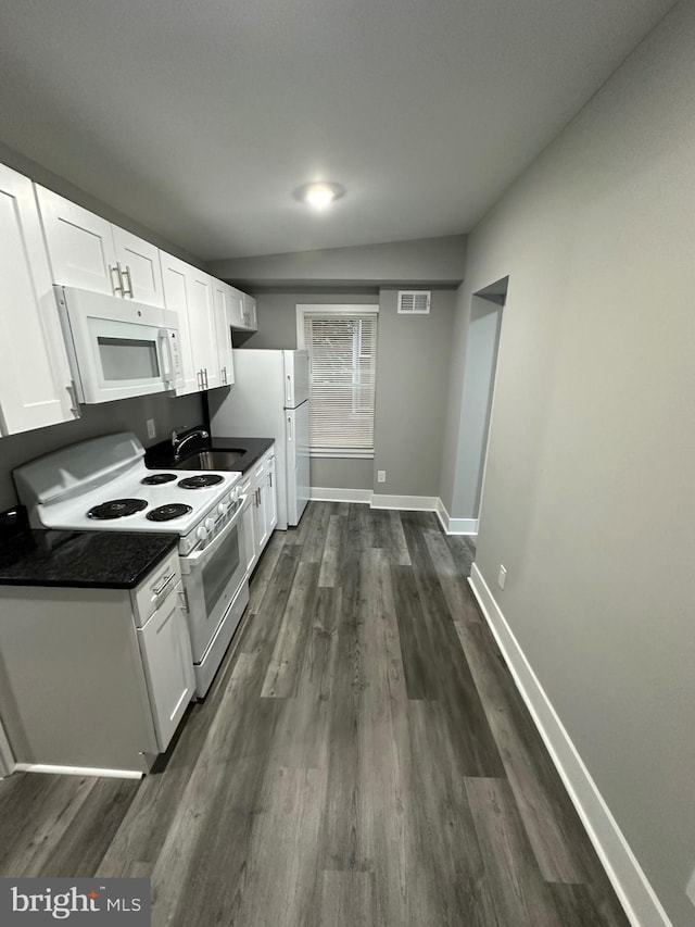 kitchen with white cabinetry, white appliances, lofted ceiling, dark hardwood / wood-style floors, and sink