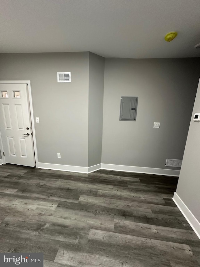 spare room with electric panel and dark wood-type flooring