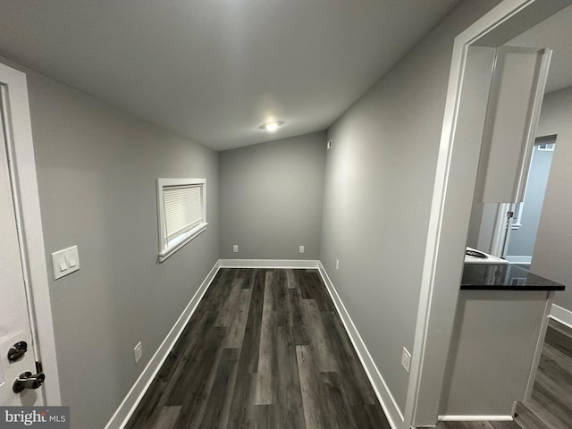 hallway featuring vaulted ceiling and dark hardwood / wood-style flooring