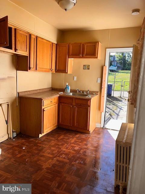 kitchen featuring dark parquet floors, radiator heating unit, and sink