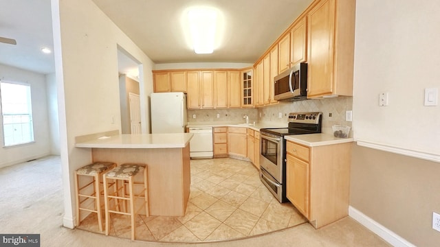 107 Sequoia Dr, Berlin, NJ 08009 - kitchen featuring appliances with stainless steel finishes, light brown cabinets, a breakfast bar area, a peninsula, and backsplash