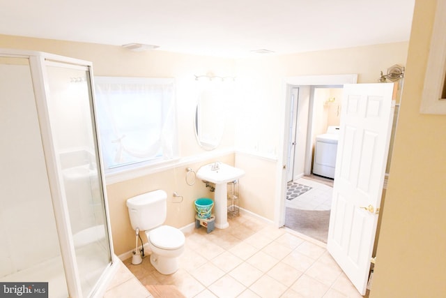 bathroom with toilet, tile patterned floors, sink, washer / clothes dryer, and a shower with shower door