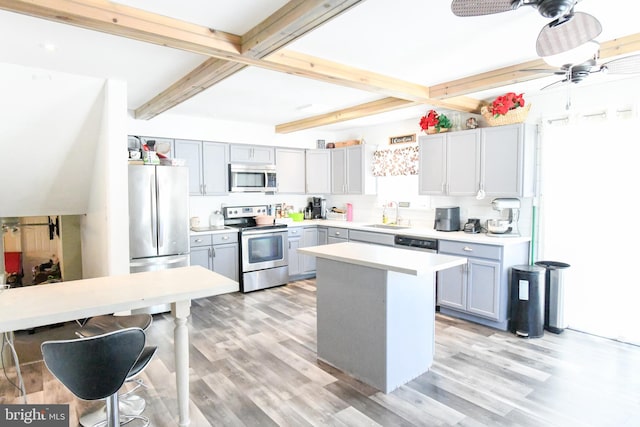 kitchen featuring a kitchen island, beamed ceiling, ceiling fan, light hardwood / wood-style floors, and appliances with stainless steel finishes