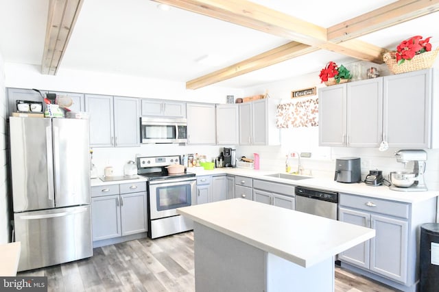 kitchen featuring a kitchen island, sink, light hardwood / wood-style floors, appliances with stainless steel finishes, and beam ceiling