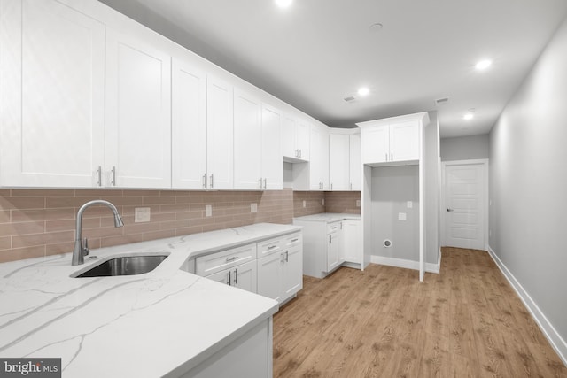 kitchen featuring light stone counters, white cabinetry, light hardwood / wood-style floors, and tasteful backsplash