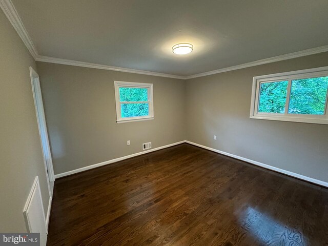 empty room featuring dark hardwood / wood-style floors and crown molding