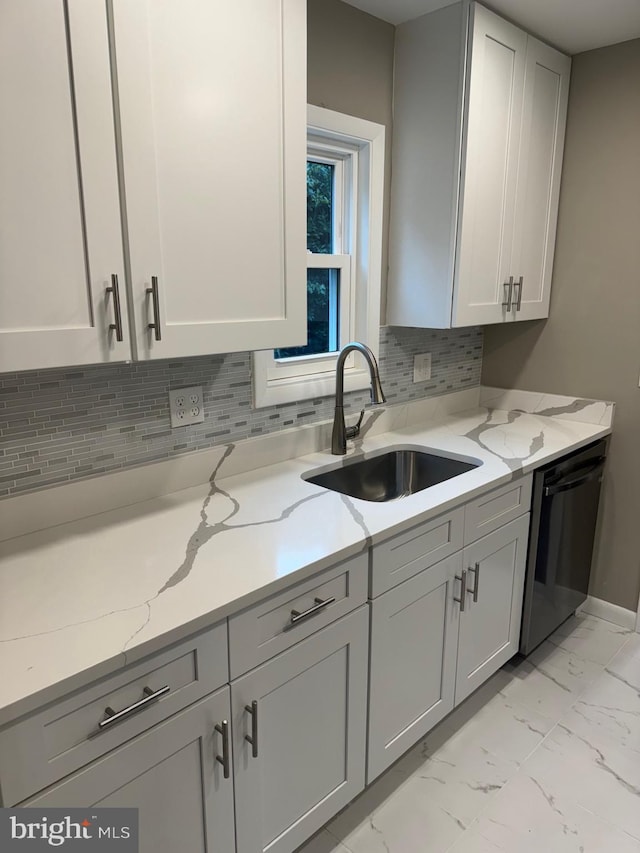 kitchen featuring dishwasher, sink, decorative backsplash, gray cabinetry, and light stone countertops