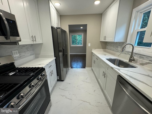 kitchen featuring appliances with stainless steel finishes, sink, light stone counters, and white cabinets