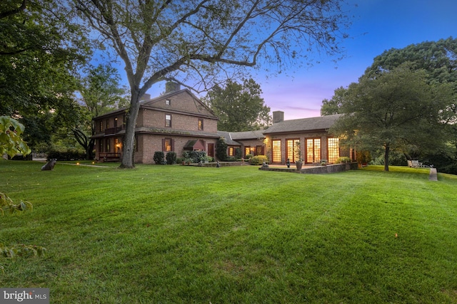 back house at dusk featuring a yard