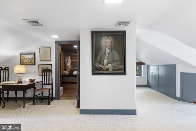 hall featuring lofted ceiling and light colored carpet