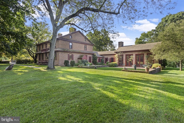 rear view of property with french doors and a yard