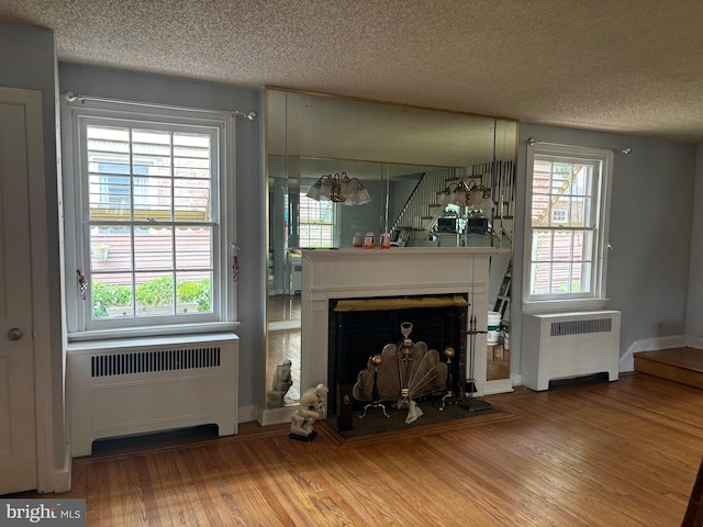 living room with wood-type flooring, radiator, and a textured ceiling