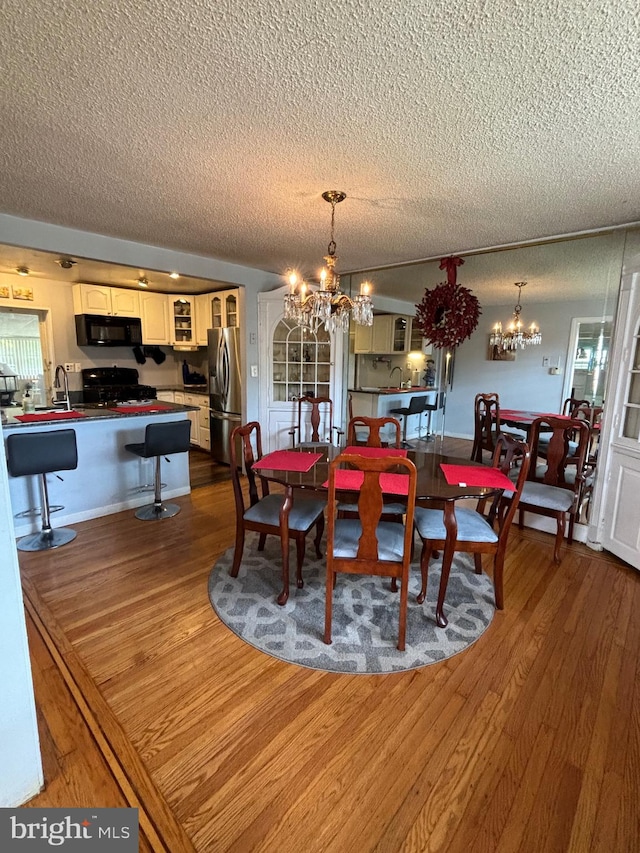 dining room featuring a chandelier, a textured ceiling, hardwood / wood-style floors, and sink